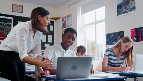 Lehrerin-hilft-männliche-Schüler-mit-Computer-im-Klassenzimmer