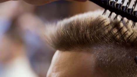 Estilista-seca-el-cabello-con-secador-de-pelo-en-el-salón-de