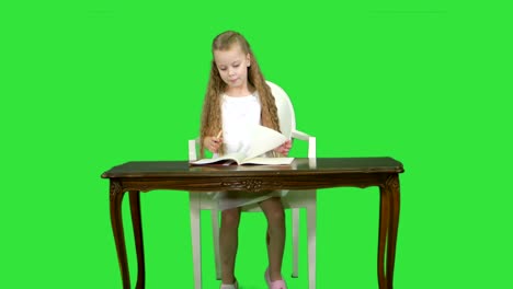 Cute-little-girl-doing-homework,-writing-down-on-a-Green-Screen,-Chroma-Key