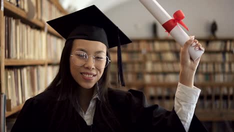 Studentin-in-akademischen-Kleid-lächelnd-posiert-positiv-stehen-in-der-Bibliothek