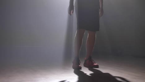 Close-footage-of-basketball-player's-legs-playing-with-ball-in-dark-misty-room-with-smoke