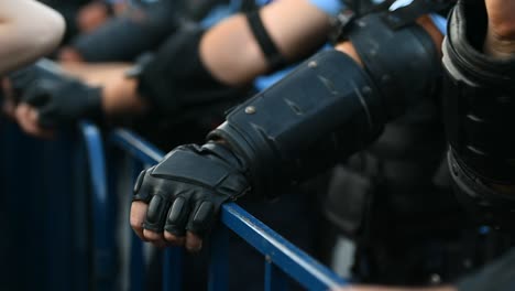 Police-officer-hands-on-a-security-fence-during-a-riot