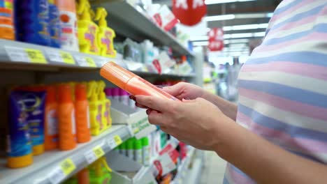 Closeup-caucasian-woman-near-shop-shelves-choosing-cosmetics-in-market