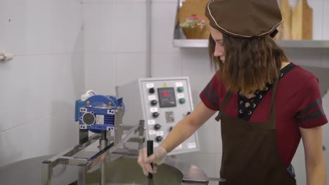 joven-es-corte-capa-de-queso-en-la-quesería-automático-en-limpio-moderno-laboratorio-en-una-granja