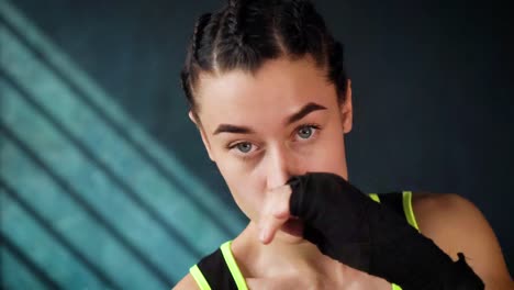 closeup-portrait-beautiful-young-boxing-woman-training-punching-in-fitness-studio