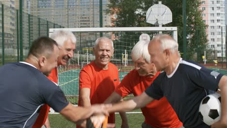 Elderly-Footballers-Making-Stack-of-Hands