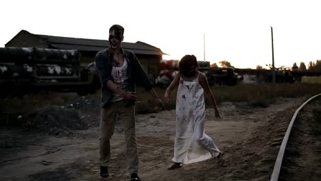 Creepy-two-zombies-in-bloody-clothes-walking-through-the-ruined-city-during-the-zombie-apocalypse.-Abandoned-place-with-trucks-with-missiles-on-the-background