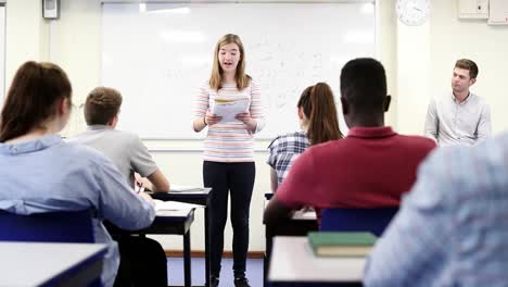 Female-Student-Giving-Presentation-To-High-School-Class-In-Science-Lesson