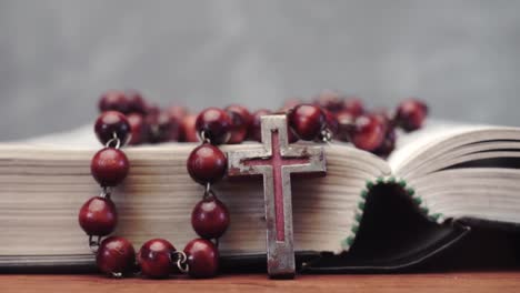 Bible-and-the-crucifix-beads-on-a-red-wooden-table.-Beautiful-background.-Religion-concept-close-up