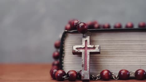 Bible-and-the-crucifix-beads-on-a-red-wooden-table.-Beautiful-background.-Religion-concept-close-up