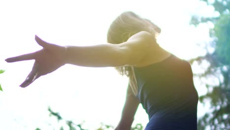 Young-beautiful-woman-feels-free-outdoors,-united-with-nature,-looks-up-sun-sky