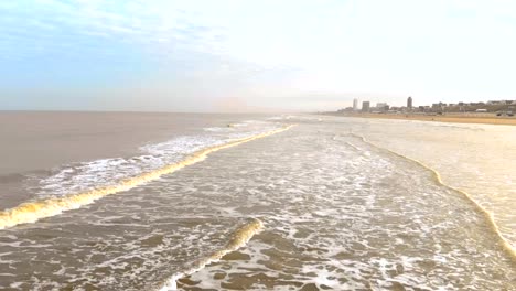 Luftaufnahme.-Slow-Motion-Flug-über-das-Meer-und-die-Wellen,-die-kommen-zum-Ufer-in-den-sonnigen-Morgen.-Niederlande-Zandvoort.-Nordsee.-Uferlinie