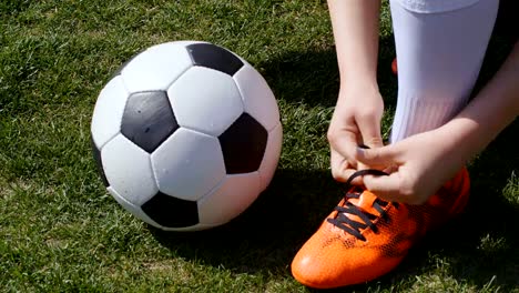 Football,-soccer-game.-Professional-footballer-young-woman-buckle-her-red-shoes-before-training,-4k