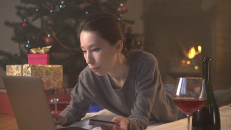 Niña-compra-presente-con-tarjeta-de-crédito-en-línea-cerca-de-árbol-de-Navidad