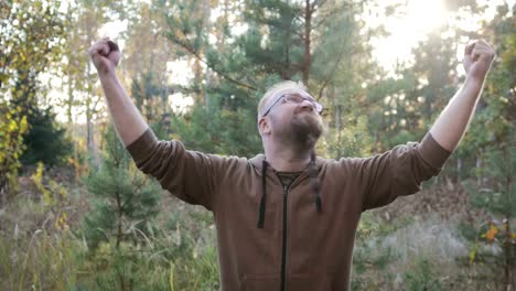 Portrait-of-a-young-man-with-a-beard-who-raised-his-hands-up-to-the-sky.-The-concept-of-joy-and-happiness