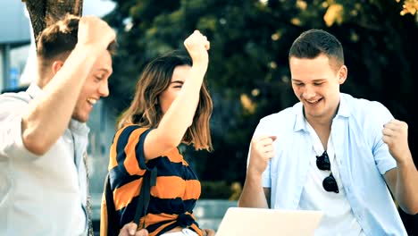 Surprising-university-students-using-laptop-together-outside-building-with-natural-light,-slow-motion.