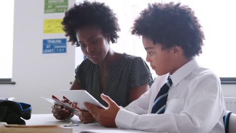 Weibliche-High-School-Lehrer-mit-Digital-Tablette-geben-männlichen-Studenten-tragen-einheitliche-Einzelunterricht-am-Schreibtisch