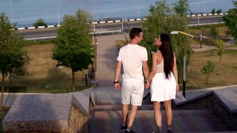 Ein-Liebespaar,-die-Treppe-zu-Fuß-in-den-Park-bei-Sonnenuntergang-herabsteigt.-Langsame-Mo.