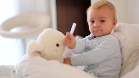 Mother-and-baby-in-pajamas,-early-in-the-morning,-mom-taking-care-of-her-sick-toddler-boy.-Baby-in-bed-with-fever-and-running-nose