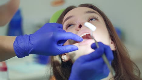 Female-dentist-takes-out-cotton-tampon-from-open-patient-mouth