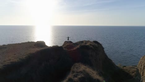 outdoor-sports-practice,-silhouette-of-men-on-slope-by-sea-with-brilliant-water-against-sky-in-bright-sun-beam