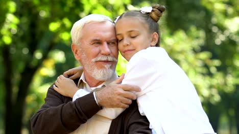 Süßes-kleines-Mädchen-umarmt-Behinderte-Großvater-sitzt-im-Rollstuhl,-Familie