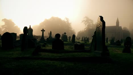 Alten-gruseligen-Friedhof-mit-Morgennebel-und-Kirche-in-der-Ferne