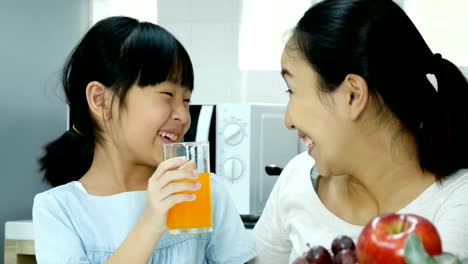 Little-girl-drinking-orange-juice-with-attractive-smiling-with-her-mother.-People-with-lifestyle-and-healthy-concept.