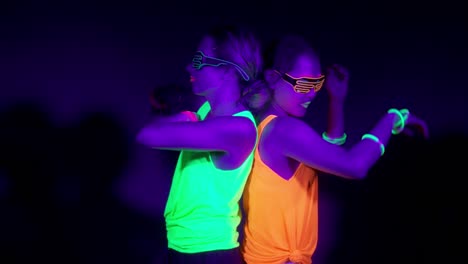 Langsame-Motin-von-schönen-sexy-Frauen-mit-fluoreszierenden-Make-up-und-Kleidung-Tanz-im-Neonlicht.-Night-Club,-Party-Konzept.