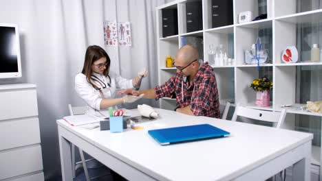 The-patient-in-the-doctor's-office.-The-doctor-examines-the-patient's-wrist.-The-doctor-examines-an-x-ray-of-the-damaged-wrist-of-the-patient.