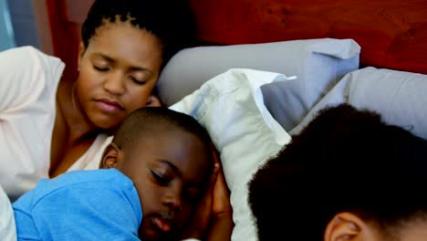 Vista-frontal-de-la-familia-negro-durmiendo-juntos-en-la-cama-en-dormitorio-de-casa-confortable-4k