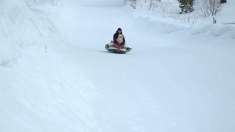 Frau-und-Mädchen-reiten-schnell-auf-dem-Schnee-Rohre