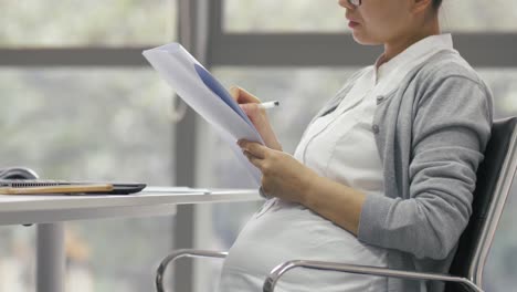 Side-view-of-Chinese-pregnant-businesswoman-working-in-the-office