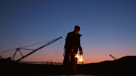 Ein-Mann-mit-einem-Flammenwerfer-bei-Sonnenuntergang-in-Zeitlupe.-Kostüm-für-Zombie-Apokalypse-und-Halloween.