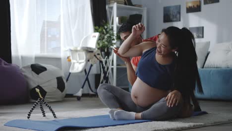 Man-and-pregnant-woman-watching-video-during-workout