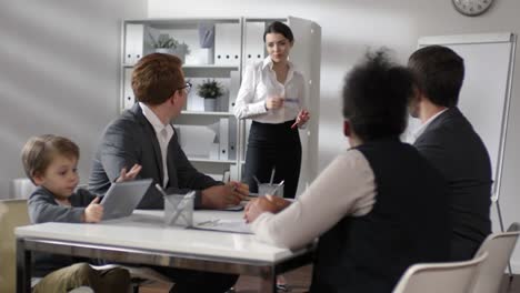 Mujer-empresaria-dando-presentación-mientras-el-hijo-juega-en-la-tableta