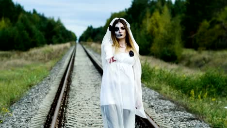 Die-junge-Frau-mit-Make-up-der-toten-Braut-für-Halloween-auf-dem-Bahngleis.-4K