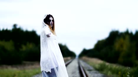 A-woman-with-make-up-of-dead-bride-for-Halloween-in-wedding-gown-on-the-rails.-4K