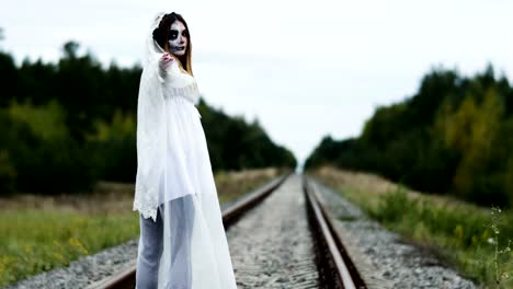 La-joven-con-maquillaje-de-novia-muerta-para-Halloween-en-la-vía-del-tren.-4K