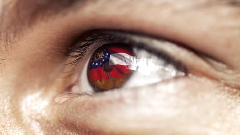 Man-with-brown-eye-in-close-up,-the-flag-of-Georgia-state-in-iris,-united-states-of-america-with-wind-motion.-video-concept