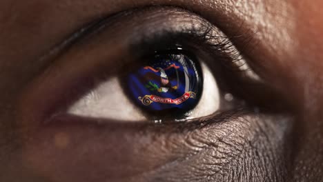 Woman-black-eye-in-close-up-with-the-flag-of-North-Dakota-state-in-iris,-united-states-of-america-with-wind-motion.-video-concept