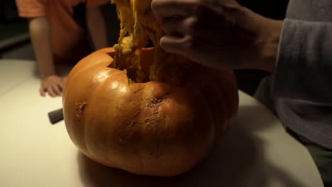 Happy-halloween.-Father-and-sons-carving-pumpkin-on-the-table-in-the-home.-Family-preparing-for-holiday.-Top-view.-Close-up