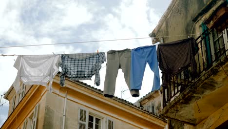 Ropa-limpia-y-ropa-de-cama-colgada-en-un-tendedero-para-secarse-al-aire-libre-en-las-calles.-4K