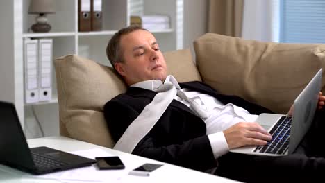 Tired-businessman-is-sleeping-on-the-sofa-at-the-office