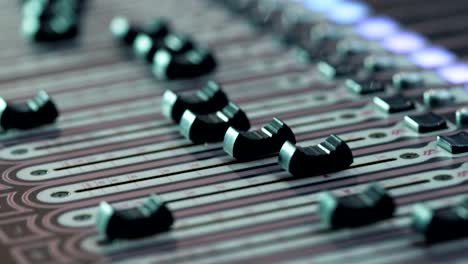 audio-mixer-in-a-studio,-the-automatic-knobs-moving-up-on-console.-Close-up-DOF