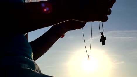 Mujer-de-silueta-orando-con-cruz-en-la-hermosa-puesta-de-sol