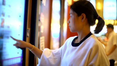 Young-Asian-Woman-using-tickets-machine-in-cinema