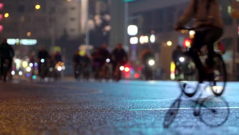 Lot-of-cyclists-ride-during-night-cycling-bike-parade-in-blur-by-illuminated-night-city-street-against-background-of-small-scale-model-of-bicycle-timalapse.-Crowd-of-people-on-bike.-Bike-traffic.-Concept-sport-healthy-lifestyle.-Bright-shining-lights.-Low