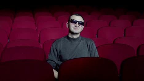 Man-in-3d-glasses-sitting-in-comfortable-red-chairs-in-dark-cinema-theater-and-looking-at-camera