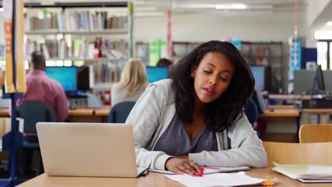 Weibliche-Schüler-arbeiten-am-Laptop-In-der-Universitätsbibliothek